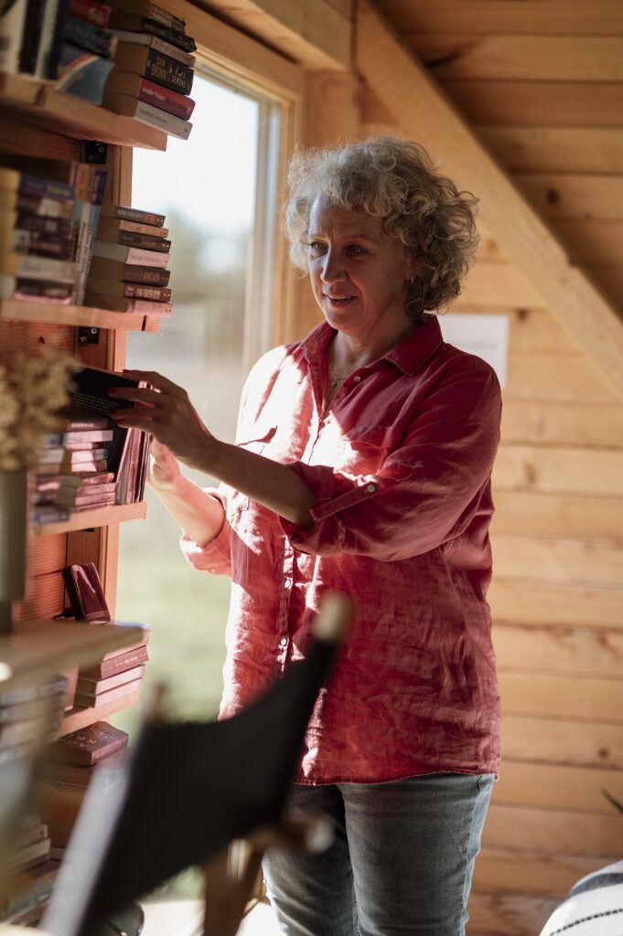 Woman browsing books in a cozy wooden cabin