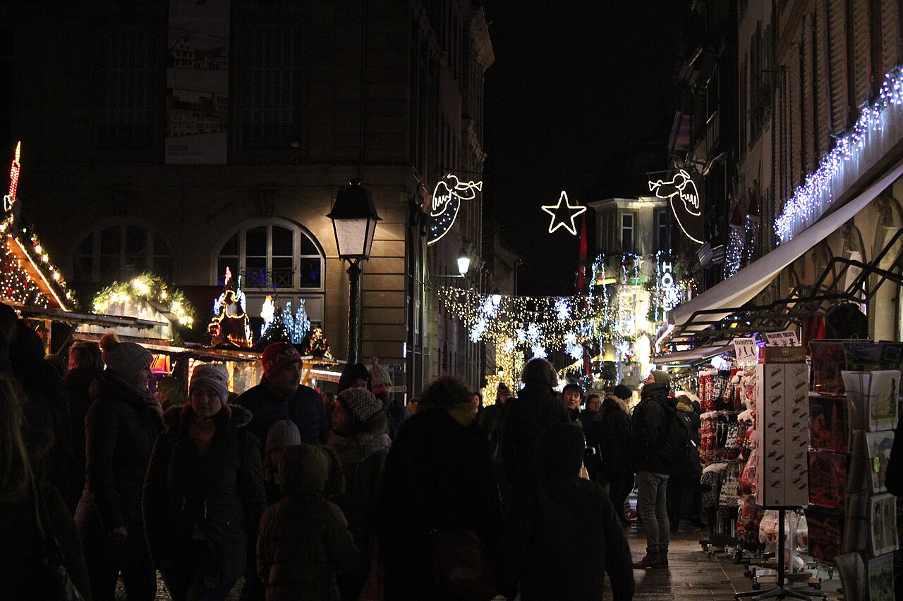 The Strasbourg Christmas market lit up at night with crowds