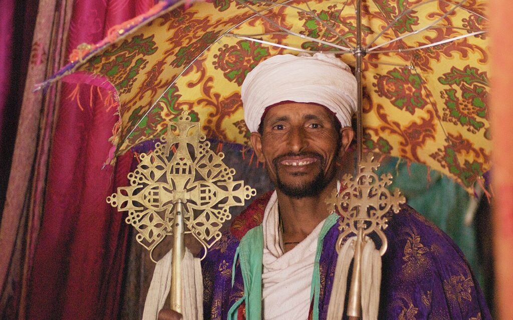An Ethiopian Orthodox priest with crosses under a ceremonial umbrella